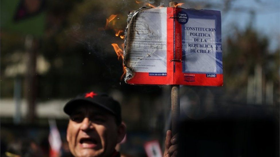 A demonstrator burns a Chilean constitution during a march and protest on the anniversary of the 1973 Chilean military coup, in Santiago, Chile September 11, 2020