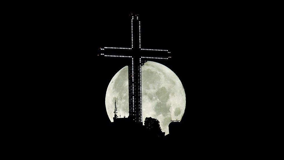 The moon rises behind the 66m (217ft) high Millennium cross in Skopje, North Macedonia
