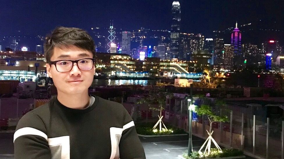 Simon Cheng stands against a city backdrop at night