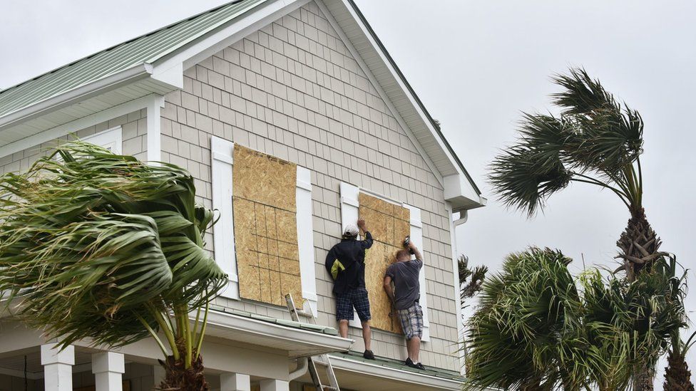 Workers from Armstrong Construction put plywood over windows of a home in preparation for Hurricane Matthew on 5 October in Ponte Vedra Beach, Florida