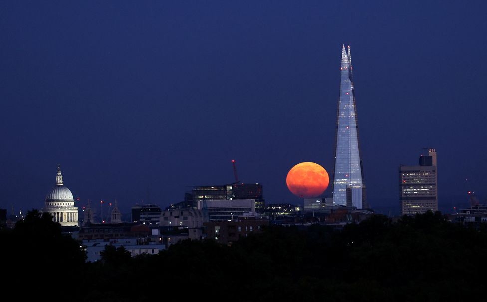 The supermoon rises near the Shard skyscraper and St Paul's Cathedral in London