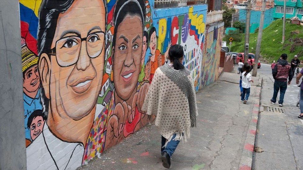 Женщина проходит мимо фрески с изображением левого президента Колумбии кандидат от коалиции «Исторический пакт» Густаво Петро (в центре) и его кандидат в вице-президенты Франсия Маркес в Сьюдад-Боливаре, Богота, 25 мая 2022 г.