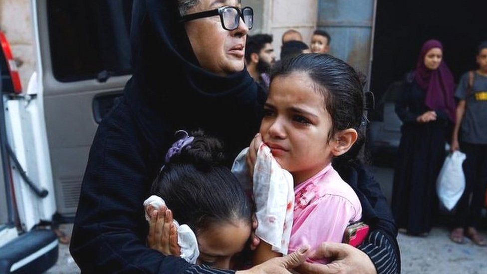 woman and children react after strike in Khan Younis