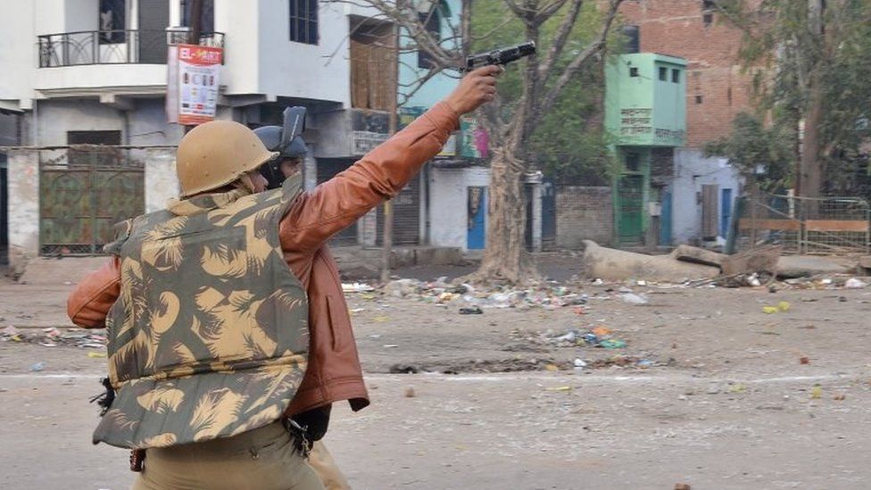 A police personnel aims his gun towards protesters during demonstrations against India"s new citizenship law in in Kanpur