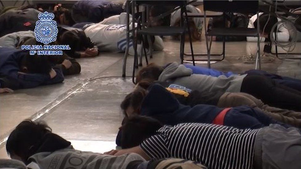 Taiwanese suspects lie on the ground during a police raid
