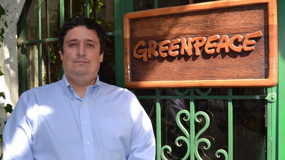 Matías Asún poses next to a Greenpeace sign