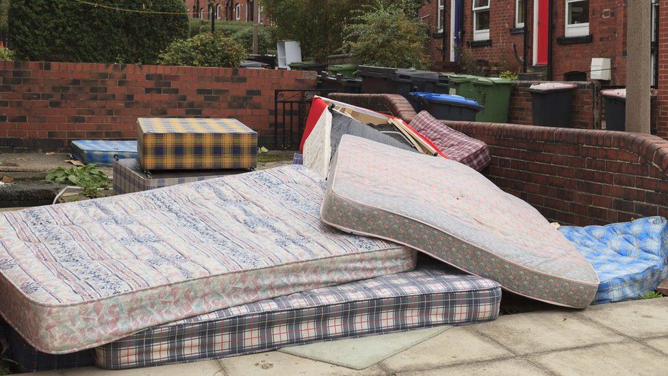 A pile of mattresses outside a house