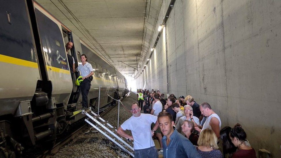 Passengers wait outside the broken down train