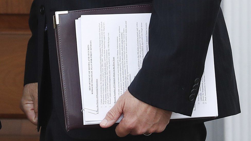Kansas' Kris Kobach carried documents while walking through a building