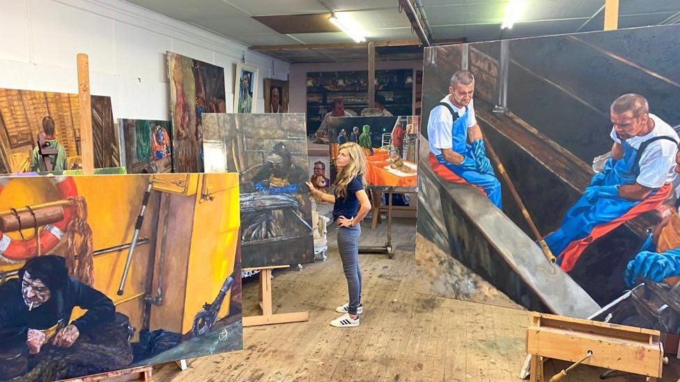 Henrietta Graham stands in studio with paintings