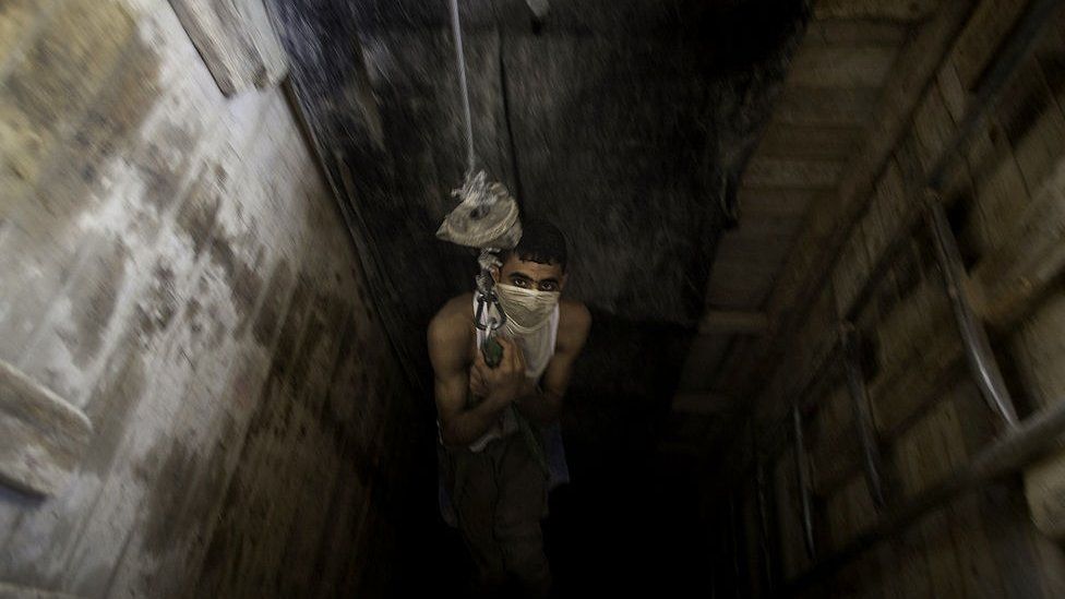 Palestinian man is lowered into a smuggling tunnel beneath the Gaza-Egypt border 4 June 2010