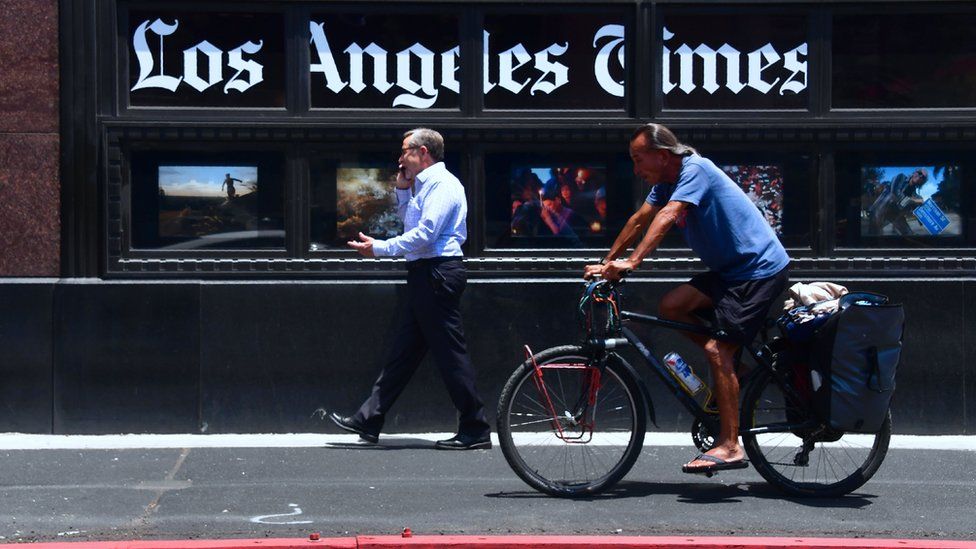 People make their way past the Los Angeles Times office building in downtown Los Angeles, California on July 16, 2018