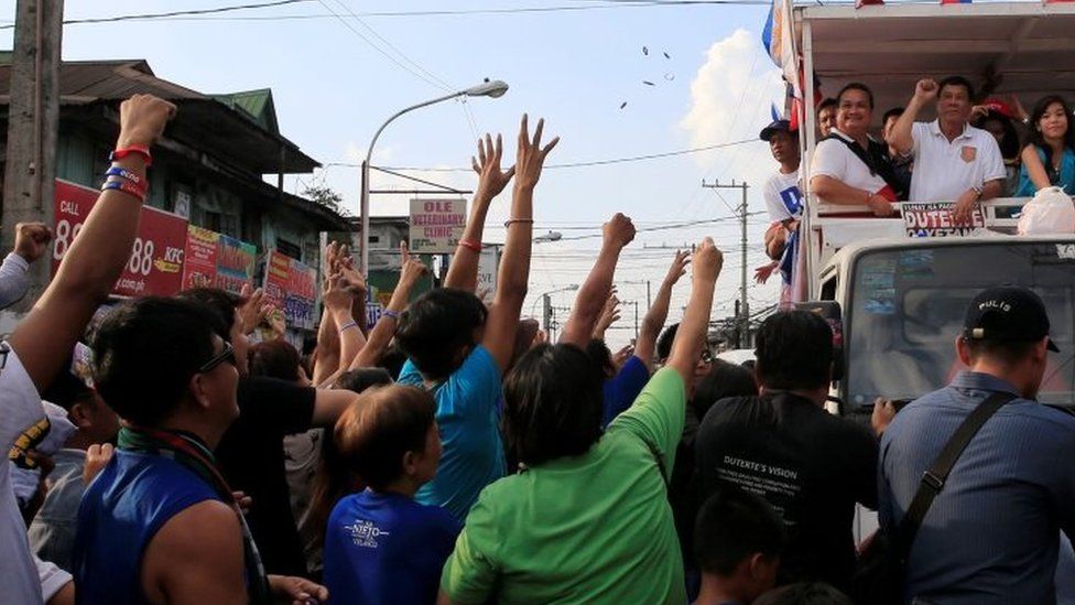 Rodrigo Duterte (top right), Philippines presidential candidate and a local mayor, raises his fist during a motorcade campaign at Cainta Rizal, east of Manila (12 April 2016)