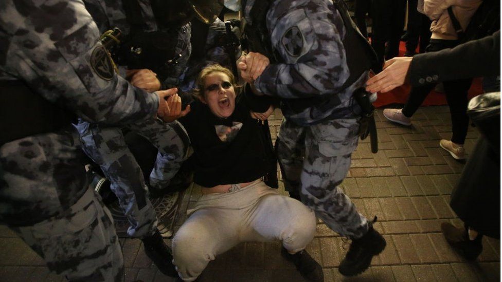A woman is detained by police officers