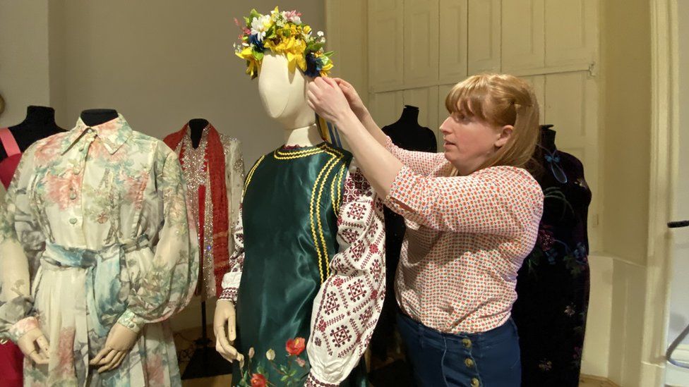 A member of staff fits the dress onto a mannequin.