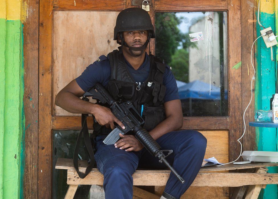 A police officer cradles his weapon while on patrol in Denham Town