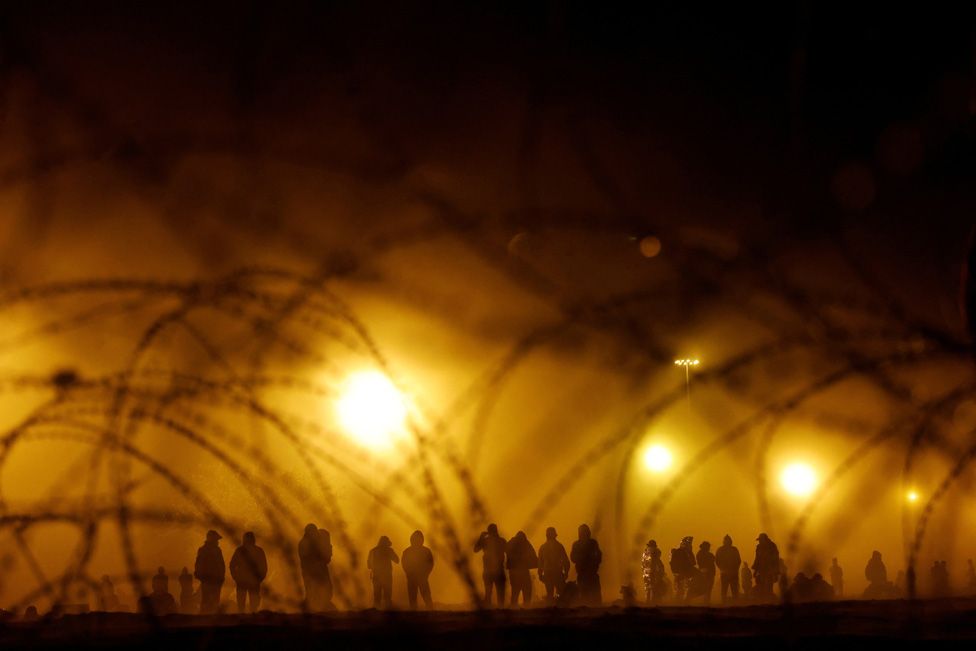 Migrants stand near the border wall during a sandstorm in El Paso, Texas, U.S., May 10, 2023.