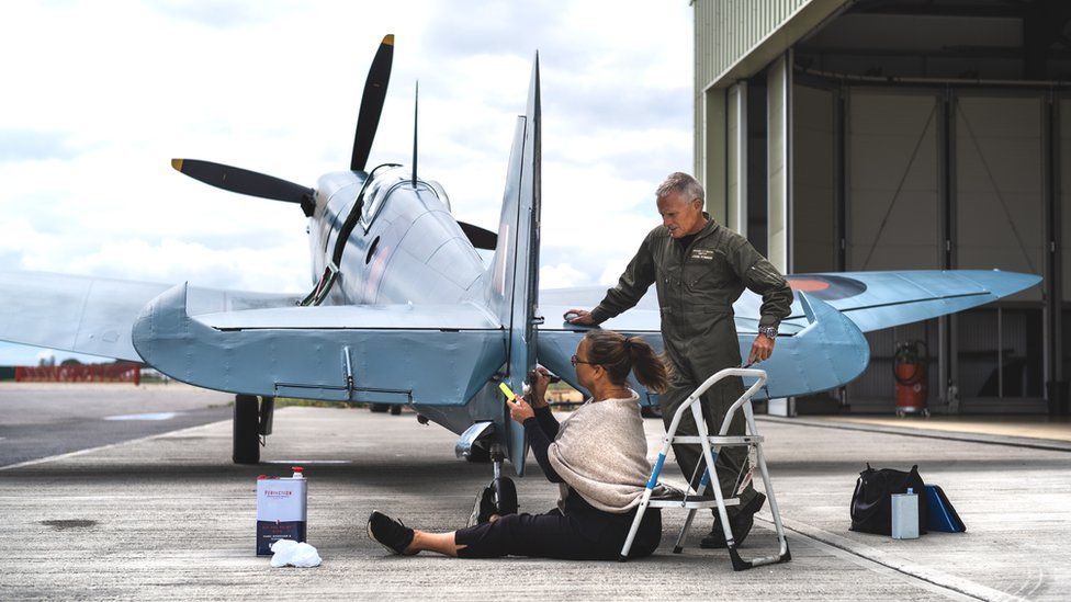 John and Amanda Romain writing names on spitfire