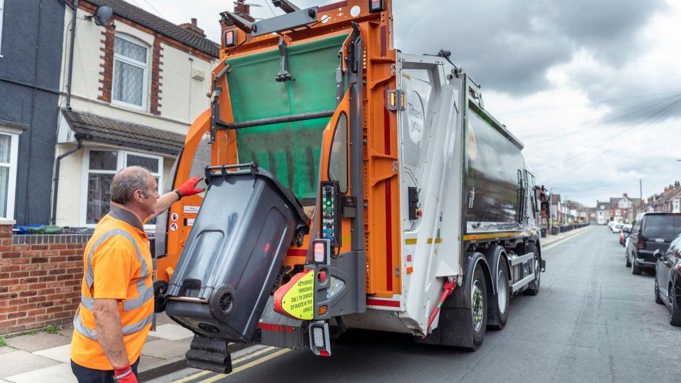 A refuse collector emptying bin into lorry