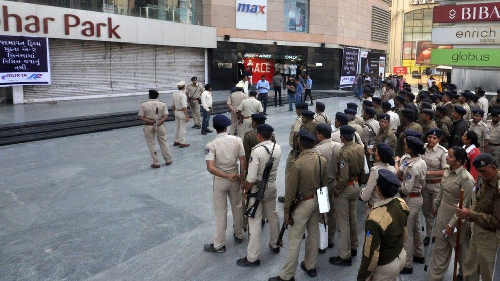 Police stand guard outside a mall in Gujarat