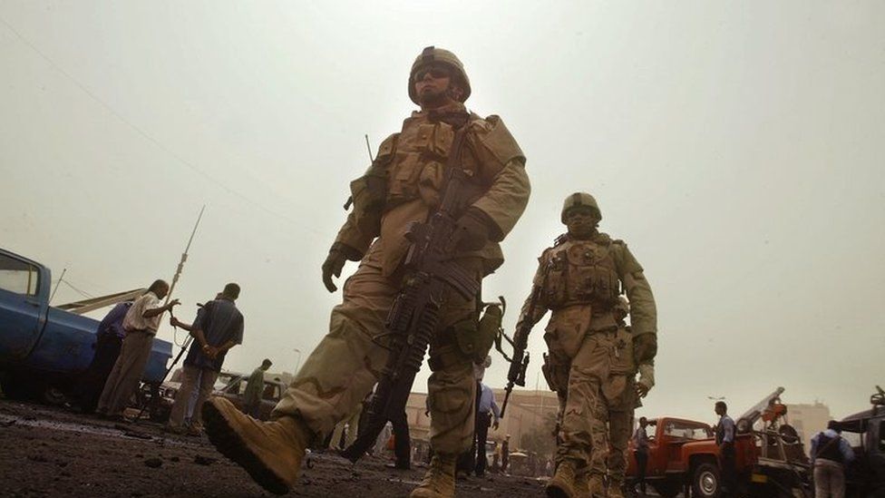 US soldiers patrol along the street of a suicide car bomb attack 9 August 2005, in central Baghdad