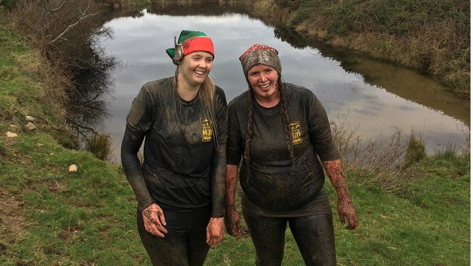 Photo of two mud-drenched women competitors