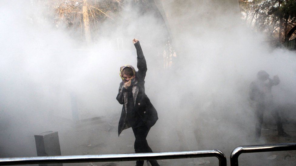 Iranian woman raises her fist amid tear gas at the University of Tehran during a protest in the capital on December 30, 2017