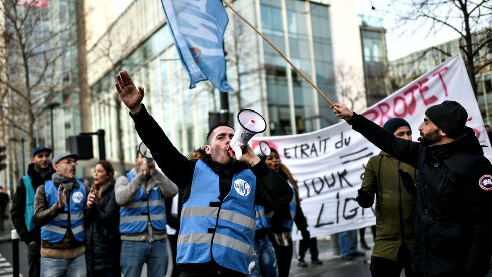 Members of a transport union gather outside French train operator SNCF headquarters in Saint-Denis, near Paris, 24 December 2019