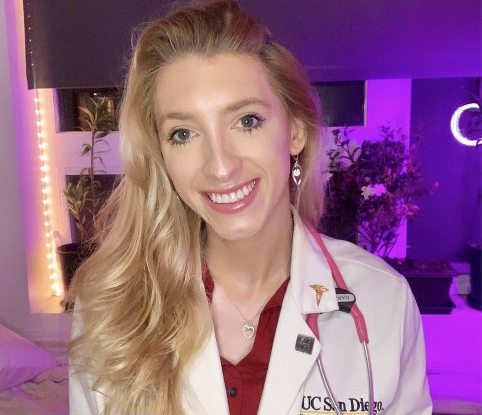 Daniella smiling at the camera with a white doctor's jacket and a stethoscope