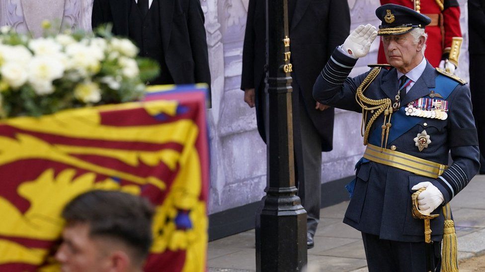 King Charles salutes a bearer party carrying the coffin of his mother