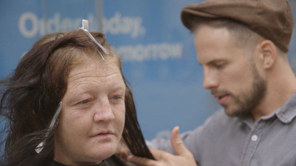 Man cutting homeless woman's hair