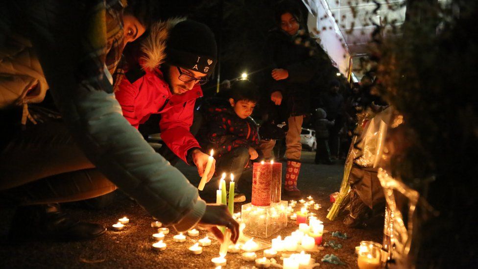 Mourners light candles and place flowers as they attend a vigil for the victims of a plane crash in Iran