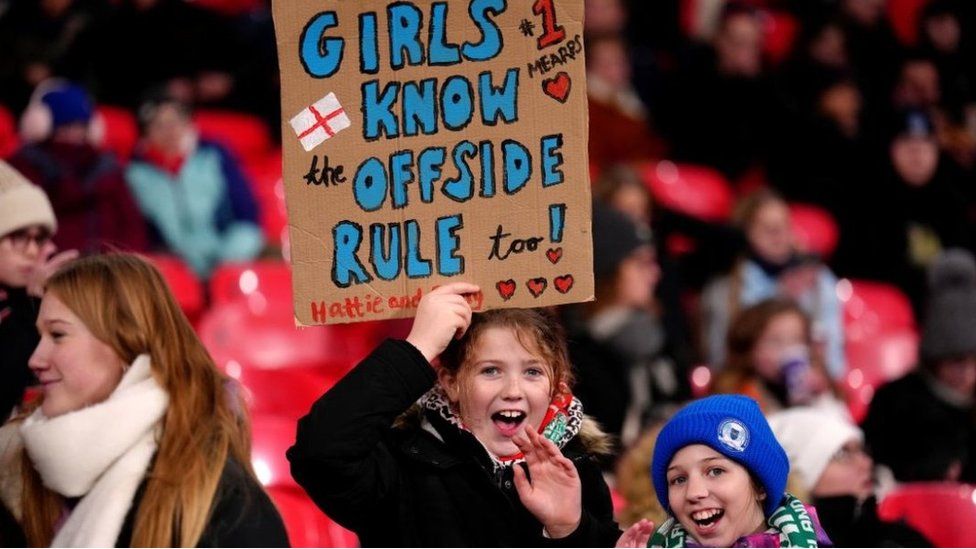 Fans hold up a sign which reads Girls know the offside rule during the UEFA Women's Nations League Group A1 match at Wembley Stadium, London