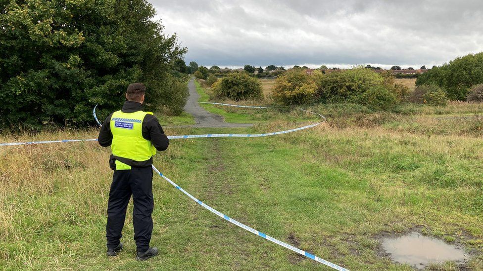 Police officer stands next to tape at scene