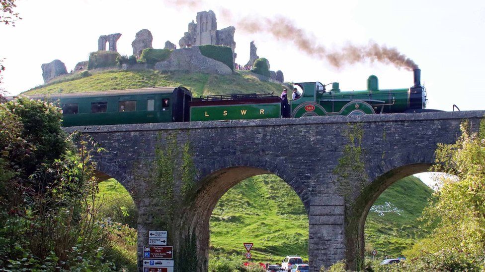 Steam train on a viaduct passing in front of Corfe Castle