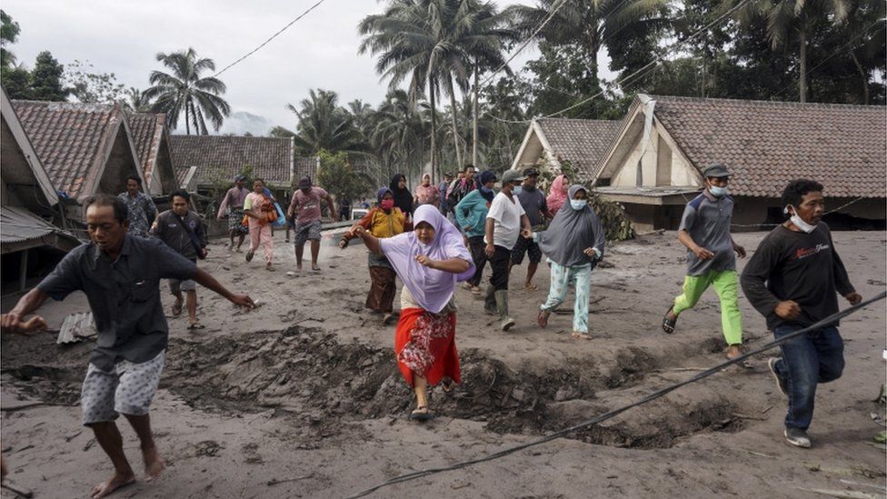 People inspect their village which has been buried with volcanic ash