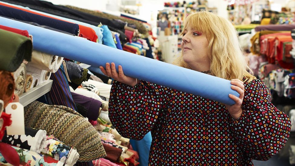 A stock image of a business owner in a fabric shop
