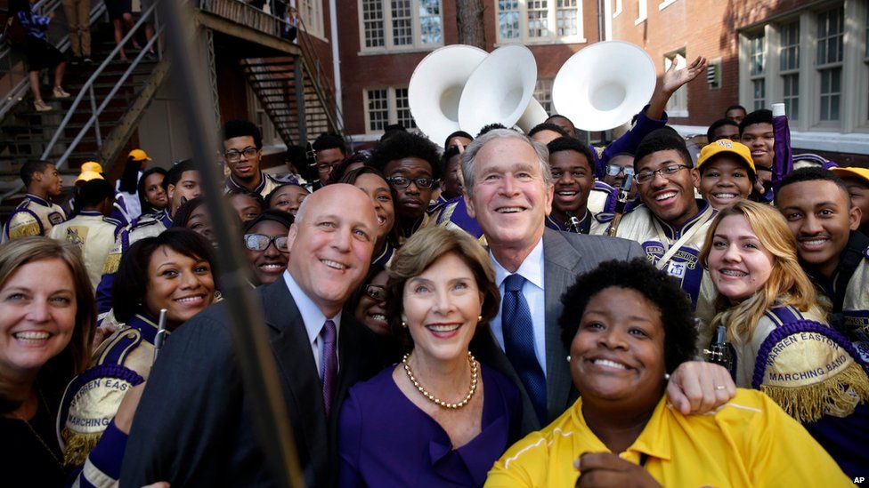 Former President George W. Bush poses for a "selfie" photo with former first lady Laura Bush, marching band director Asia Muhaimin, right, and New Orleans Mayor Mitch Landrieu, left, at Warren Easton Charter High School in New Orleans on 28 August