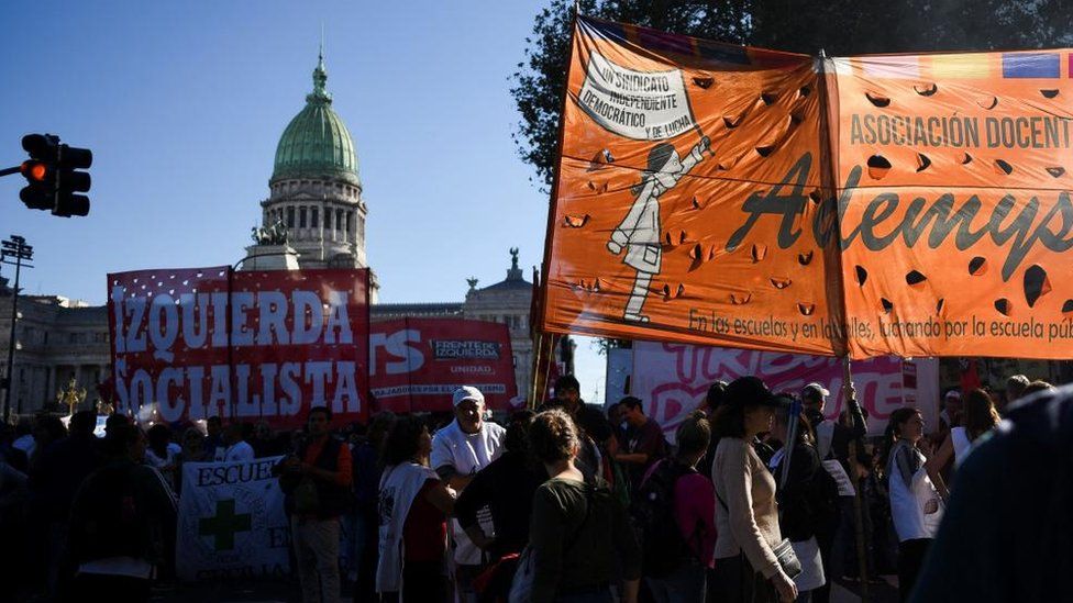 People hold banners up in front of the Argentine congress building during a protest against university cuts in Buenos Aires.