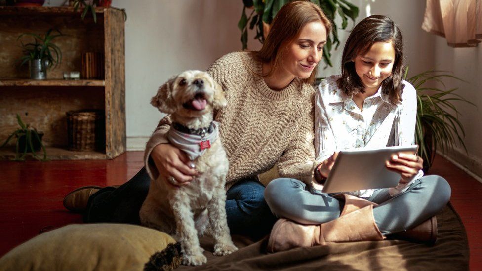 Mother, daughter and dog in front of tablet computer