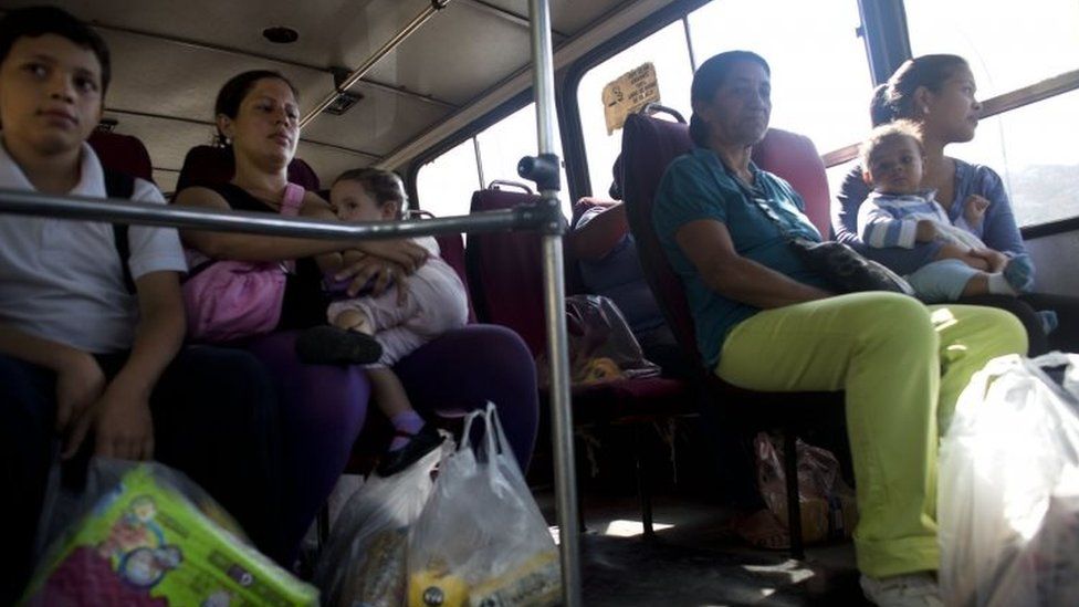 People ride home aboard a bus with their groceries after standing in line for more than four hours to buy them at government regulated prices in Caracas (19 February 2016)
