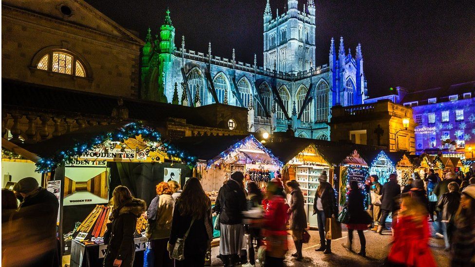 Bath Christmas Market stalls illuminated at night with Bath Abbey in the background