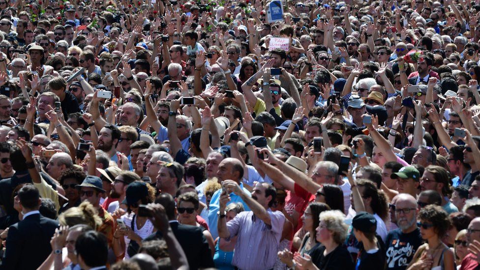 A large crowd take pictures on Las Ramblas.