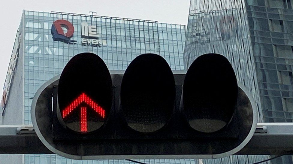 A partially removed company logo of China Evergrande Group is seen on the facade of its headquarters, near a traffic light in Shenzhen, Guangdong province.