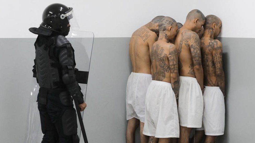 A prison agent guards gang members as they are processed at their arrival after 2000 gang members were transferred to the Terrorism Confinement Center,