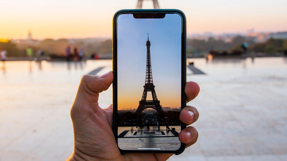 Эйфелева башня на экране камеры смартфона на фоне настоящей Эйфелевой башни