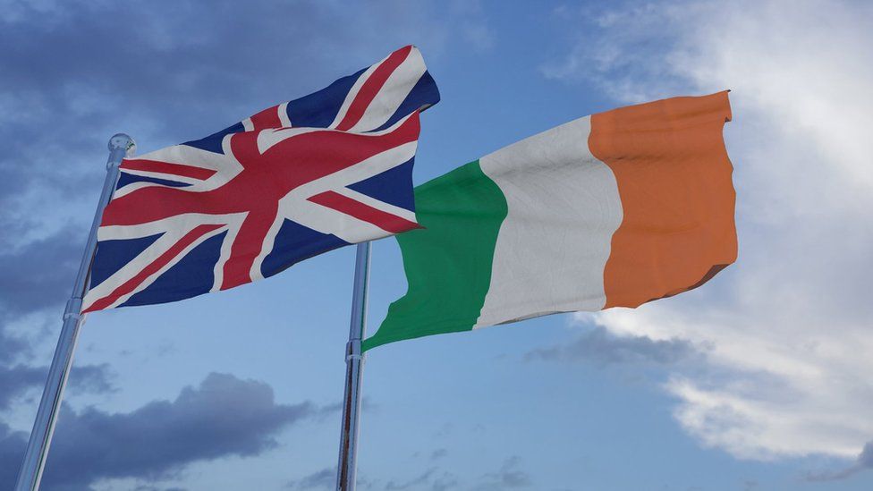 An Irish flag and UK flag blowing in the wind