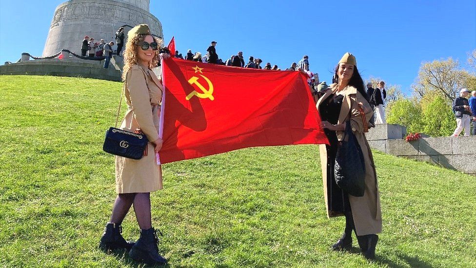 Two women in Germany hold a Russian flag in support of the Kremlin’s policies and rhetoric