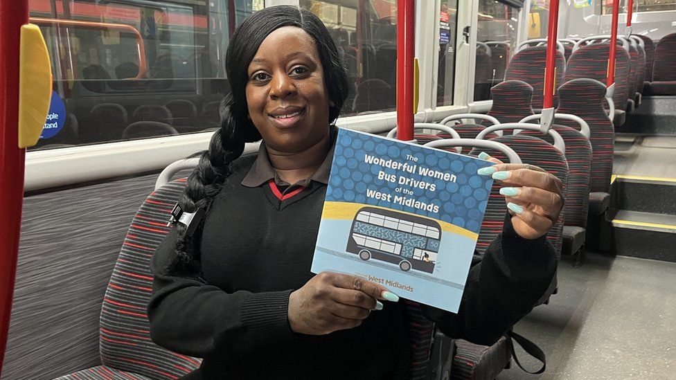 A female bus driver holding a book
