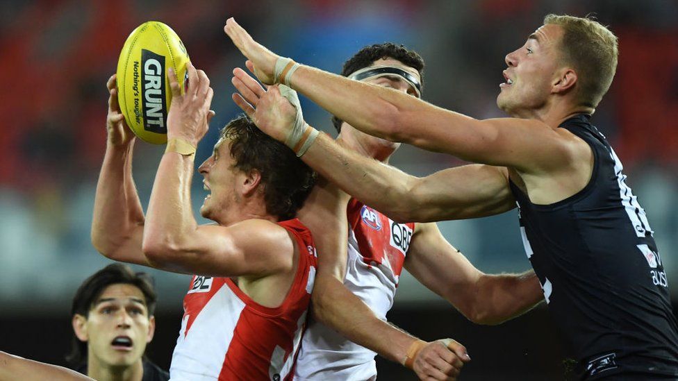 An AFL player catches the ball amid a contest with other players